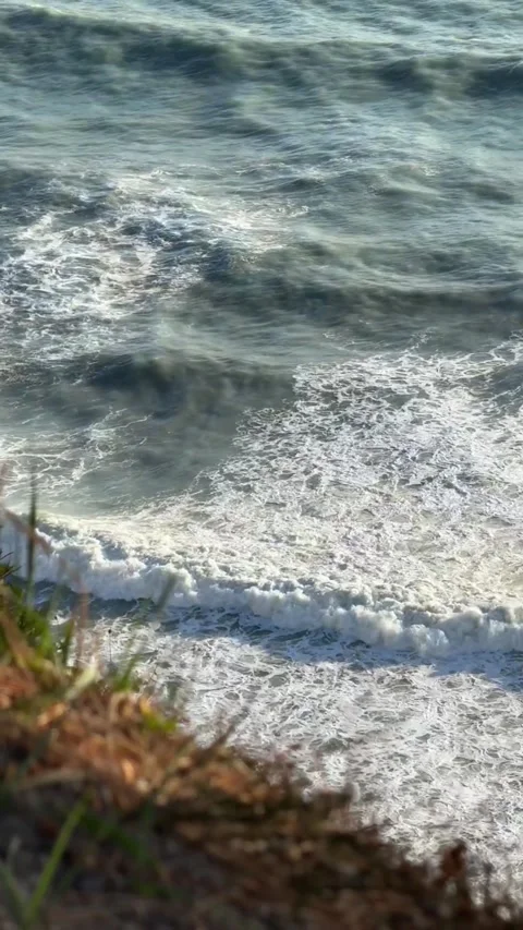 A vertical shot of rocky cliffs rising above the sea surface. A calm view of the Stock Footage 275476240