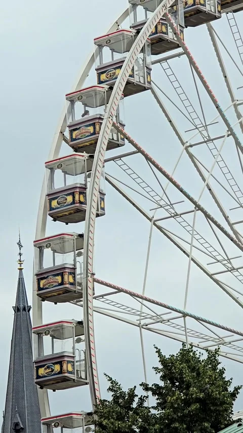 Vertical shot of a rotating Ferris wheel and a church spire Stock Footage 344612275