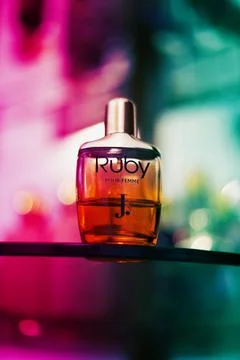 Vertical shot of a Ruby perfume on a colorful blurred bokeh background Foto stock