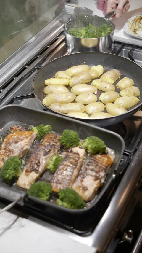Vertical shot of salmon and broccoli baking in grill pan with potato 動画素材 221750908