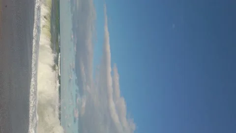 Vertical shot. sandy beach. blue sky. sea waves, white foam. vacation on coast. Vidéo 144110629