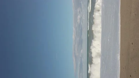 Vertical shot. sandy beach. Large sea waves, white foam. Bright blue sky. Windy Stock Footage 144112623
