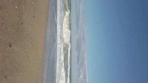 Vertical shot. sandy beach. Large sea waves, white foam. Bright blue sky. Windy Stock Footage 144112624