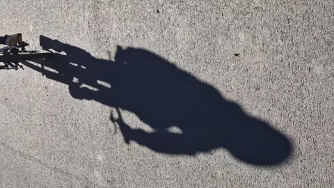 Vertical shot. Shadow of a child on a pedaling bicycle. Happy childhood. Video stock 276347992