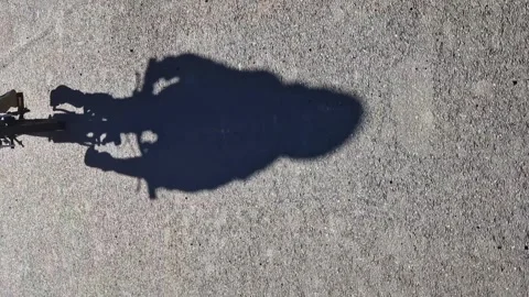 Vertical shot. Shadow of a child on the road pedaling a bicycle. Happy childhood Stock-Footage 277184565