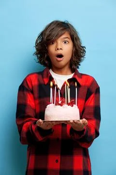 Vertical shot of shocked young guy, holds tasty cake with burning candles, can Stock-Fotos
