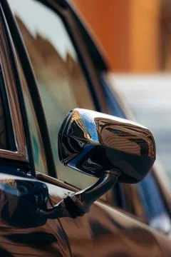 Vertical shot of a side-view mirror of an old vintage car on the blurred backgro Stock Photos