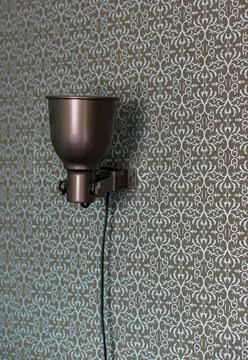 Vertical shot of a simple lamp on a patterned wall Stock Photos