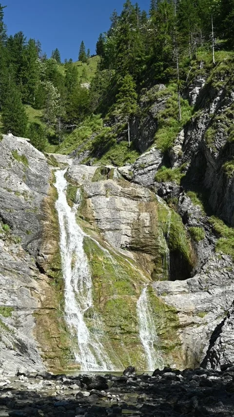 Vertical shot of a slow moving mossy waterfall in alpine surroundings, slow-mo Video stock 260893242