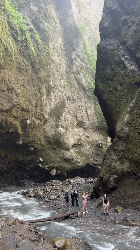 Vertical shot of a small group of hikers standing beside a rushing river at the Stock Footage 346615780