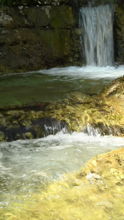Vertical shot of a small pond in front of a waterfall in the mountains Video stock 260883465