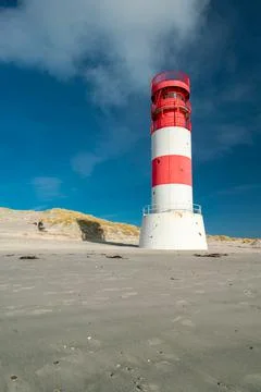 Vertical shot of small red and white lighthouse on the sandy beach of Dune Stock Photos