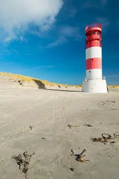 Vertical shot of small red and white lighthouse on the sandy beach of Dune Stock Photos