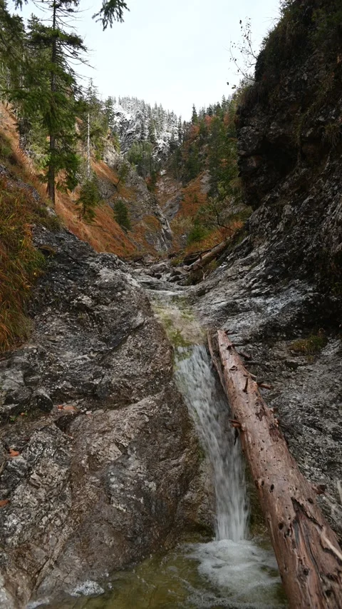Vertical shot of a small waterfall in autumn, first snow in the background Stock-Footage 260896536