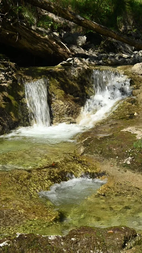 Vertical shot of a small waterfall from a mountain stream in the afternoon Stock Footage 260883263