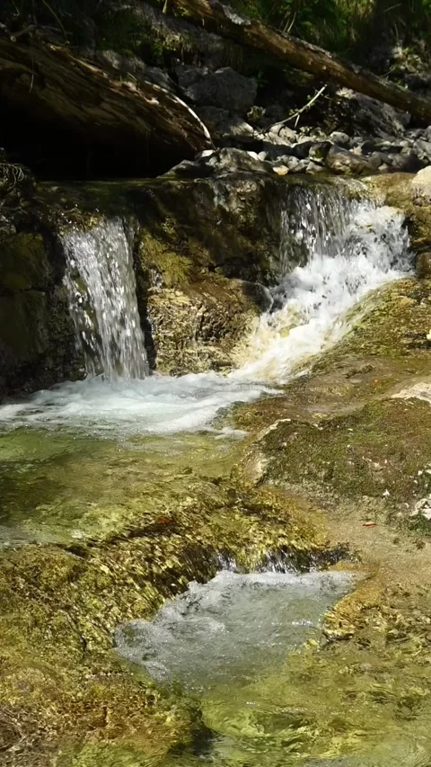 Vertical shot of a small waterfall from a mountain stream in a forest, slow-mo 스톡 동영상 260885132