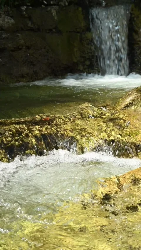 Vertical shot of a small waterfall from a mountain stream in with water swirling 스톡 동영상 260885258