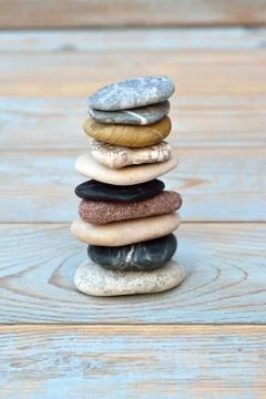 Vertical shot of a stack of flat stones on a wooden table Foto stock