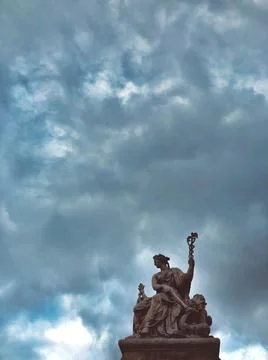Vertical shot of a statue under the cloudy skies in Paris 스톡 사진