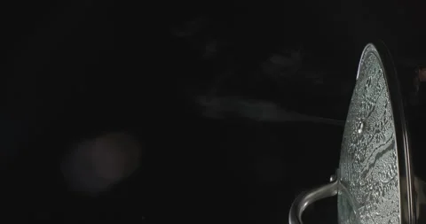 Vertical shot of steam rising from boiling water in saucepan on black background Stock Footage 249989920