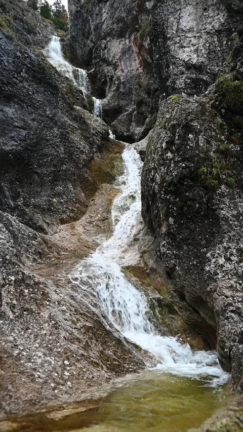 Vertical shot of a stepped waterfall in autumn, with a pond, slow motion Video stock 260895660