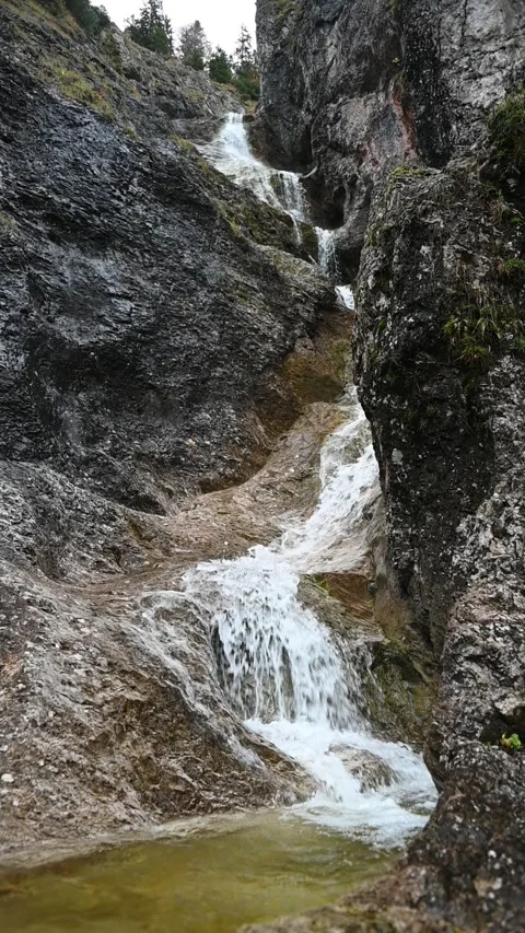 Vertical shot of a stepped waterfall in autumn, with a pond, slow motion Video stock 260896004