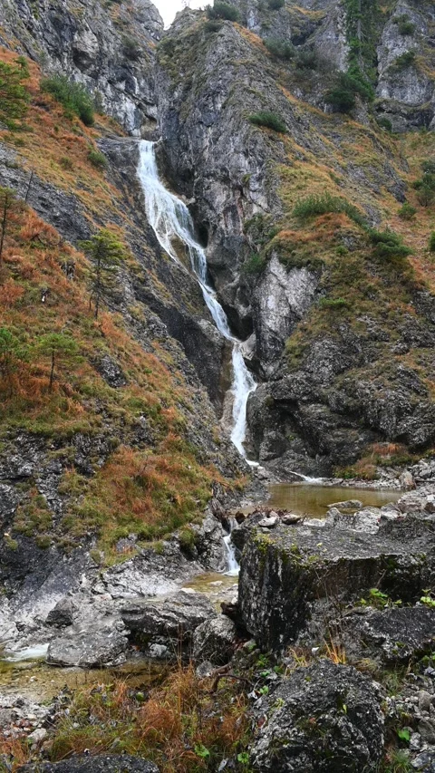 Vertical shot of a stepped waterfall in autumn, with a pond in the foreground Video stock 260896477