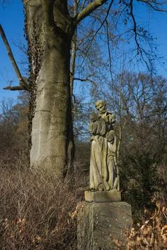 A vertical shot of a stone statue in a forest Stock Photos