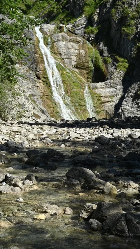 Vertical shot of a stoney mountain stream in front of a slow moving waterfall Stock-Footage 260891808