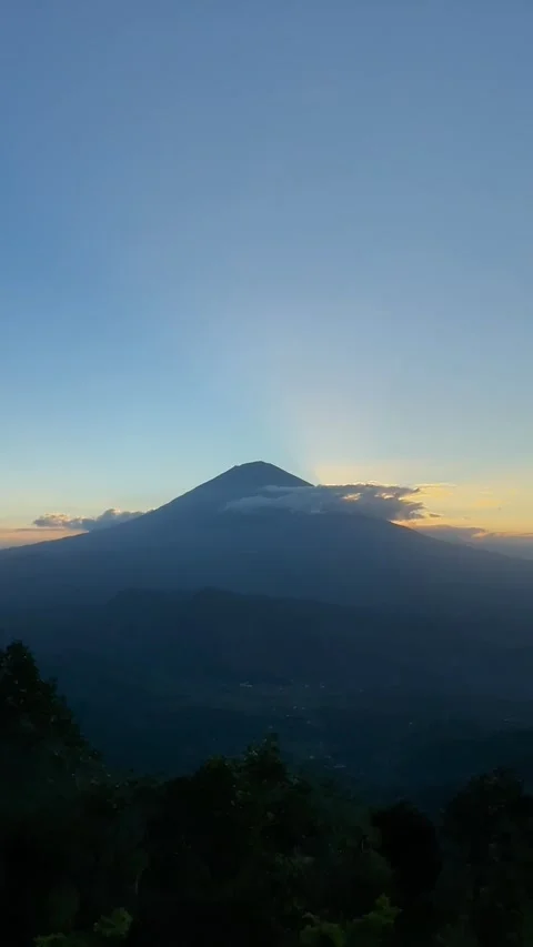 Vertical Shot of Sunbeams Bursting Behind Mount Agung Silhouette 動画素材 341552182