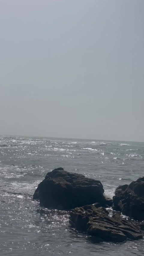 Vertical Shot of Sunlight Sparkling on Ocean Waves Near Coastal Rocks Stock Footage 340775086