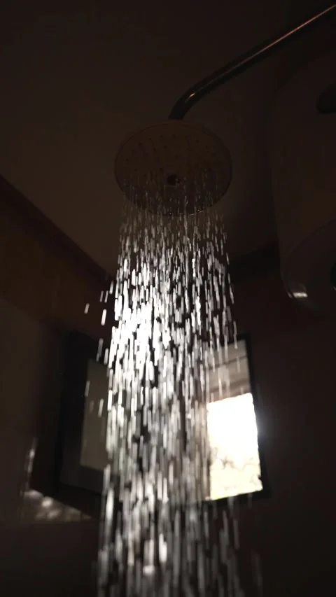 Vertical shot of Sunlit shower water stream in dark bathroom interior Stock Footage 340942471