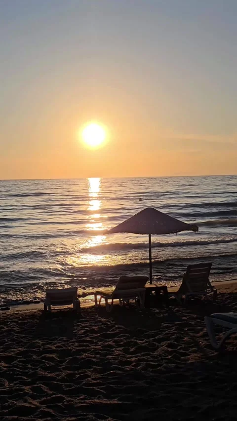 Vertical shot of Sunset over calm sea with empty beach chairs and umbrella  Stock-Footage 337402171