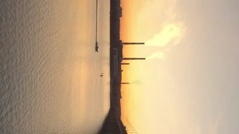 Vertical shot of sunset over river with bridge, motor boat and smoking plant Stock Footage 203969059