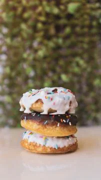 Vertical shot of three donuts on each other vertically against blur background Foto stock