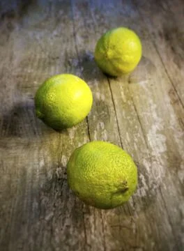 Vertical shot of three fresh limes on a wooden table Stock Photos