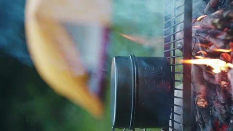 Vertical shot of touristic boiler over burning campfire on background tent Stock Footage 247316403