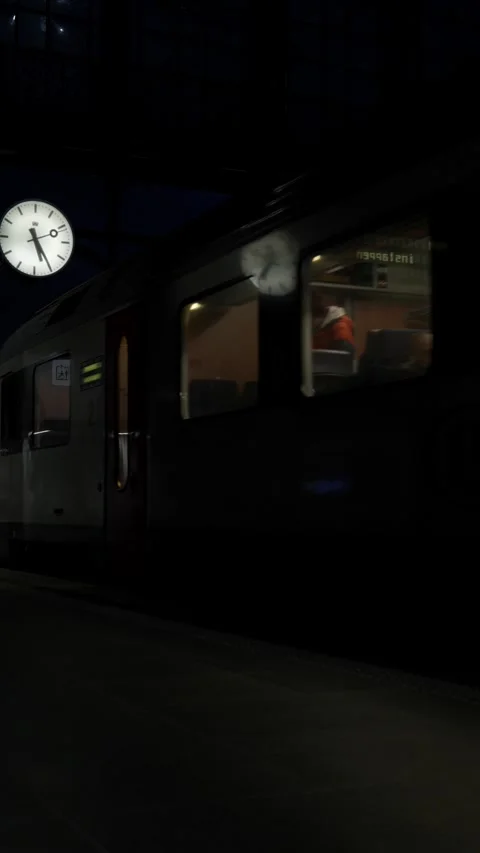 Vertical shot of train leaving station in darkness with clock reflection Видео 223139328