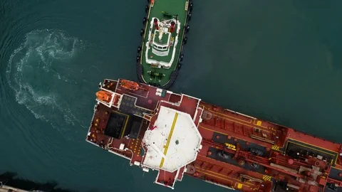Vertical shot of tug boat pushing a large freighter ship into position at wharf. Stock Footage 87877706