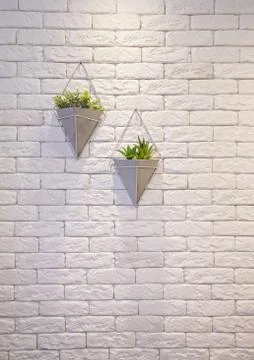 A vertical shot of two decorative triangular flowerpots suspended from a whit Stock Photos