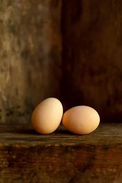 Vertical shot of two eggs with an old wooden background Stock Photos