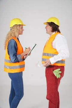 Vertical shot of two engineers, a man and a woman, talking on white background Stock Photos