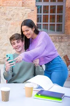Vertical shot Two friends browsing an internet application with a smartphone. Stock Photos