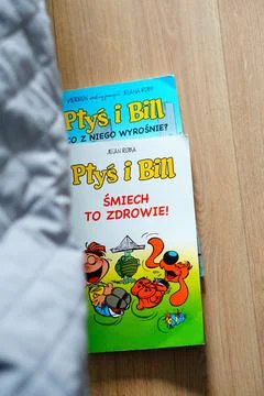 Vertical shot of two Polish comic books called Ptys I Bill laying on a wooden fl Stock Photos