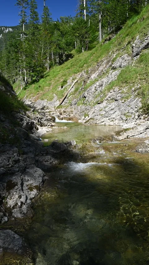 Vertical shot of a v-shaped mountain stream in summer with a shadowy foreground Video stock 260878139