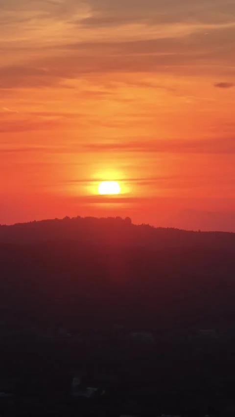 Vertical shot of vibrant orange sunset setting behind dark silhouetted Stock Footage 345002265
