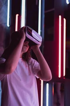 Vertical shot - a virtual reality helmet on a woman close-up. Neon light Stock Photos