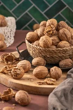Vertical shot of walnuts in a rustic woven basket set on a wooden tray with.. Stock Photos