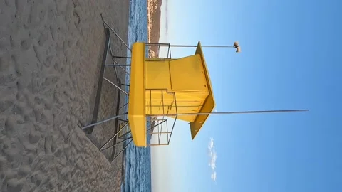 Vertical shot of a watchtower on a beach. Yellow lifeguard tower with blue ocean Stock Footage 225634465