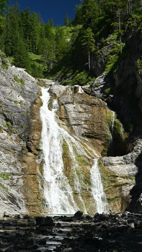 Vertical shot of a waterfall with a mountain stream in front in Bavaria Video stock 260877205